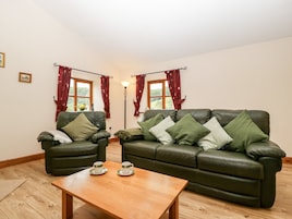 A living room with a green leather sofa, two armchairs, a wooden coffee table, and two cups on saucers.