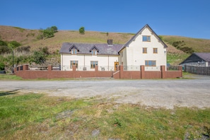 A two-story house with a sloped roof, a brick exterior, and a fenced yard.