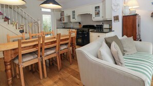 A kitchen with wooden furniture, a dining table, and a sofa. - Rose Cottage (Cardigan)