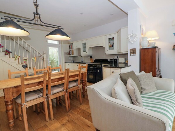 A kitchen with wooden furniture, a dining table, and a sofa. - Rose Cottage (Cardigan)