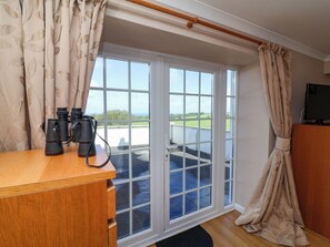 A room with a wooden desk, binoculars, a television, and a large window with a view of the outdoors. - Old Chapel (Bideford)