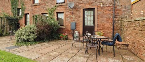 A stone building with a patio area, outdoor seating, and a door with a window.