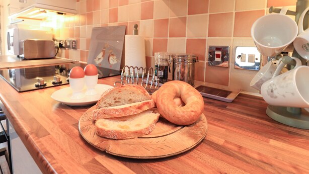 Una encimera de cocina con pan, huevos y una cafetera.