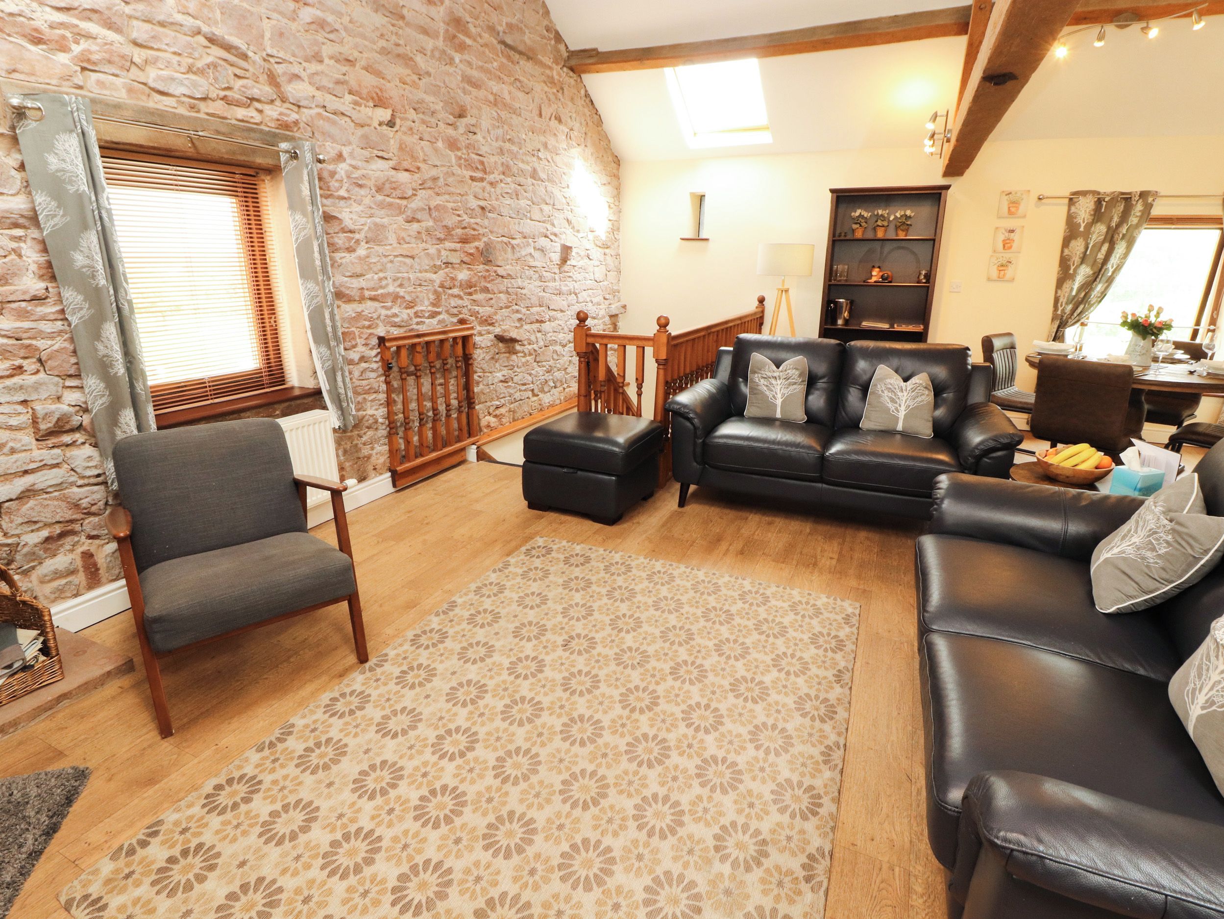 A cozy living room with a stone wall, leather sofas, a wooden coffee table, and a patterned rug.