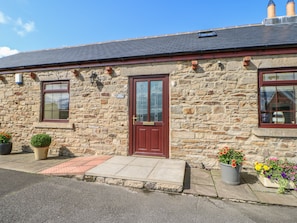 Charming cottage with a traditional design, featuring a red door and two windows.