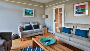 A living room with two grey sofas, a wooden coffee table, and a blue patterned rug. - Wren Cottage (Harrogate)