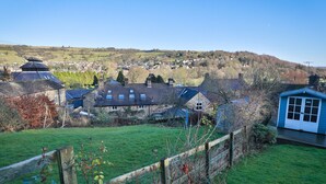 A rural landscape with stone houses, a wooden fence, and a small blue shed. - Wren Cottage (Harrogate)