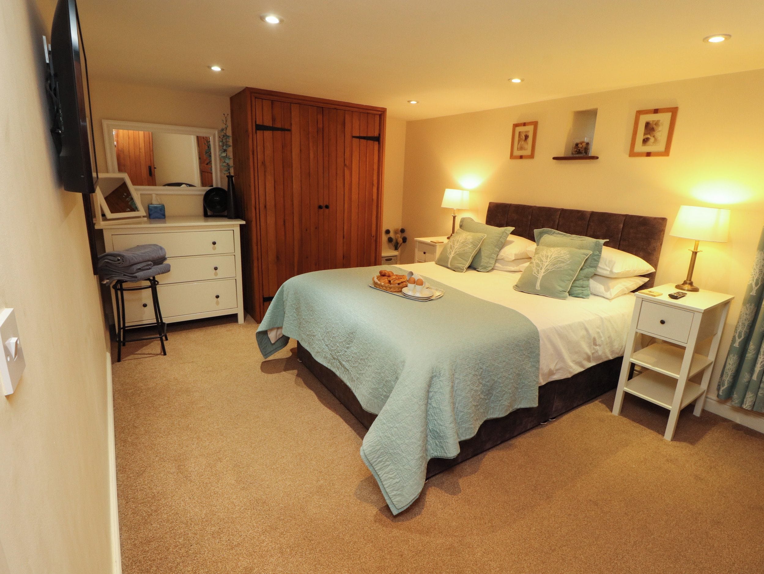 A bedroom with a bed, bedside tables, a wardrobe, and a television.