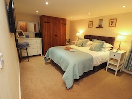 A bedroom with a bed, bedside tables, a wardrobe, and a television.