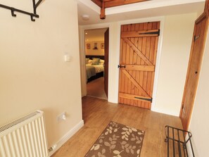 A hallway with a radiator, a wooden door, and a bed in the adjacent room.