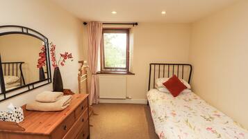 A bedroom with a bed, a dresser, a mirror, a radiator, and a window with curtains.