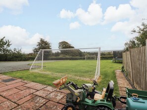 Cortacésped en un jardín con una portería de fútbol.