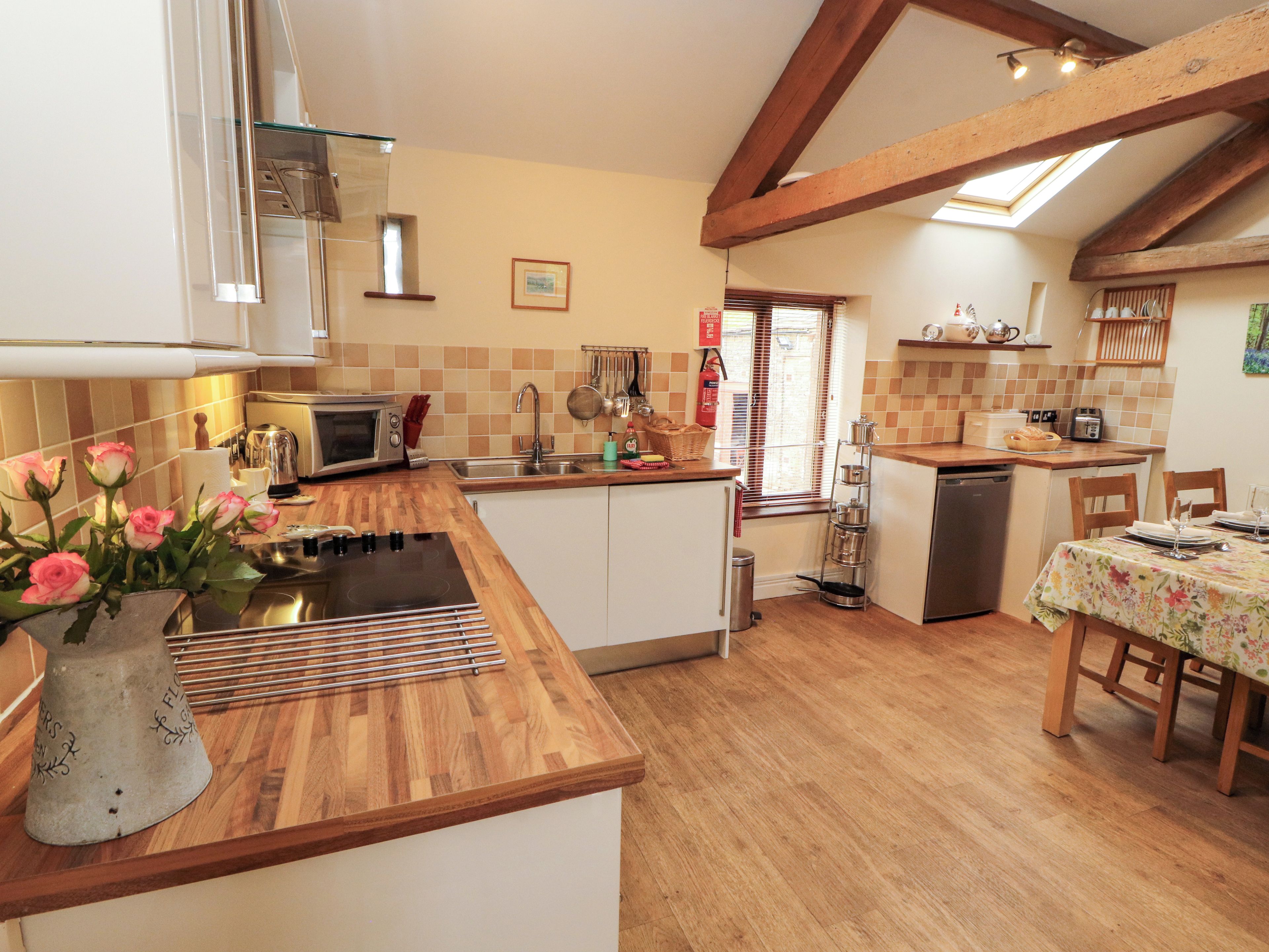 A kitchen with wooden countertops, a built-in oven, a sink, and a dining area with a table set for two.