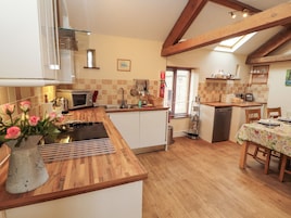 A kitchen with wooden countertops, a built-in oven, a sink, and a dining area with a table set for two.