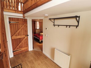 A hallway with a wooden door, a radiator, and a bed in the background. - Horseshoe Cottage (Wigton)