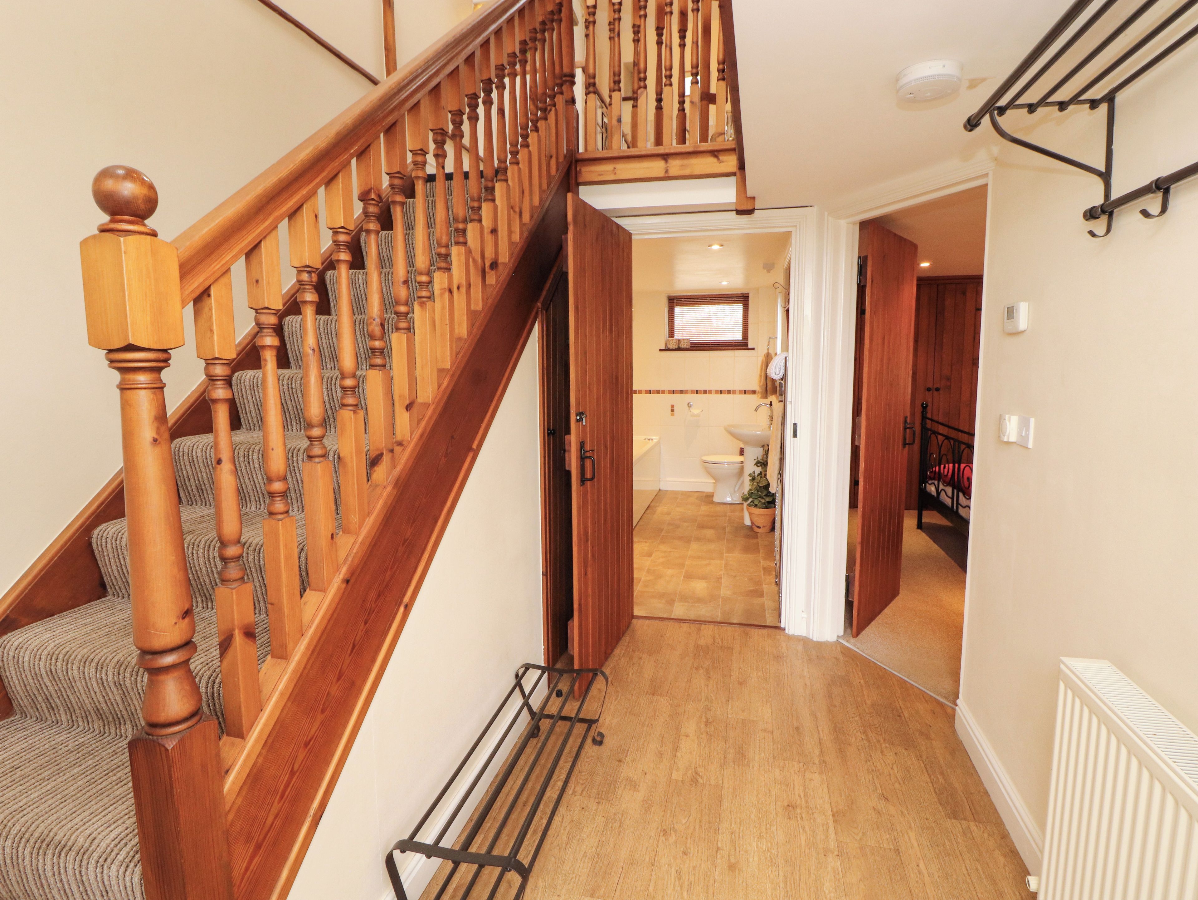 A wooden staircase with a handrail, leading to a room with a radiator, a window, and a door.