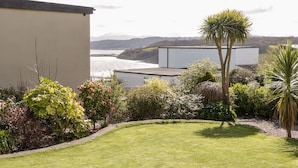 Un jardin avec une pelouse, divers arbustes et un palmier.