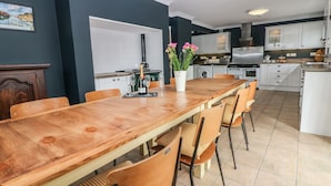 Une cuisine moderne avec des meubles blancs, une table à manger en bois et une plante en pot.