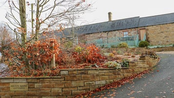 Experience the charm of Milton Mains Cottages, surrounded by a serene garden with a variety of plants and shrubs.
