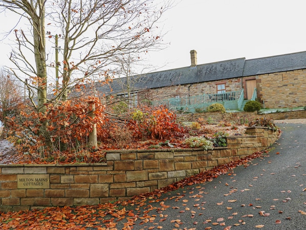 A stone building with a brick pathway and a sign reading "Milton Mains Cottages". - Swift Cottage (Brampton)