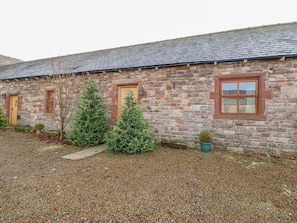 A stone building with a gravel driveway and two potted plants. - Swift Cottage (Brampton)