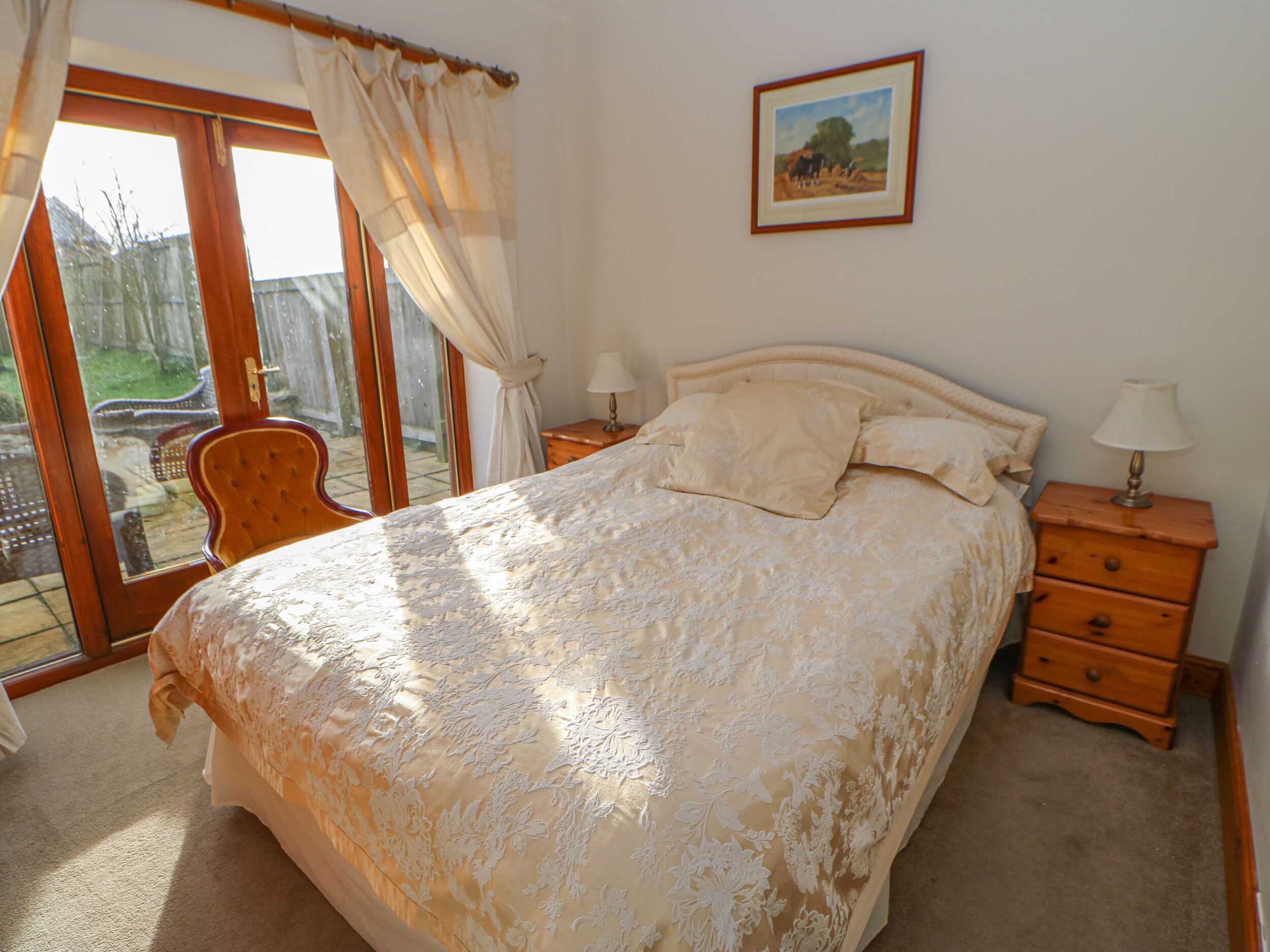 A bedroom with a large bed, a chair, a nightstand, and a picture on the wall.