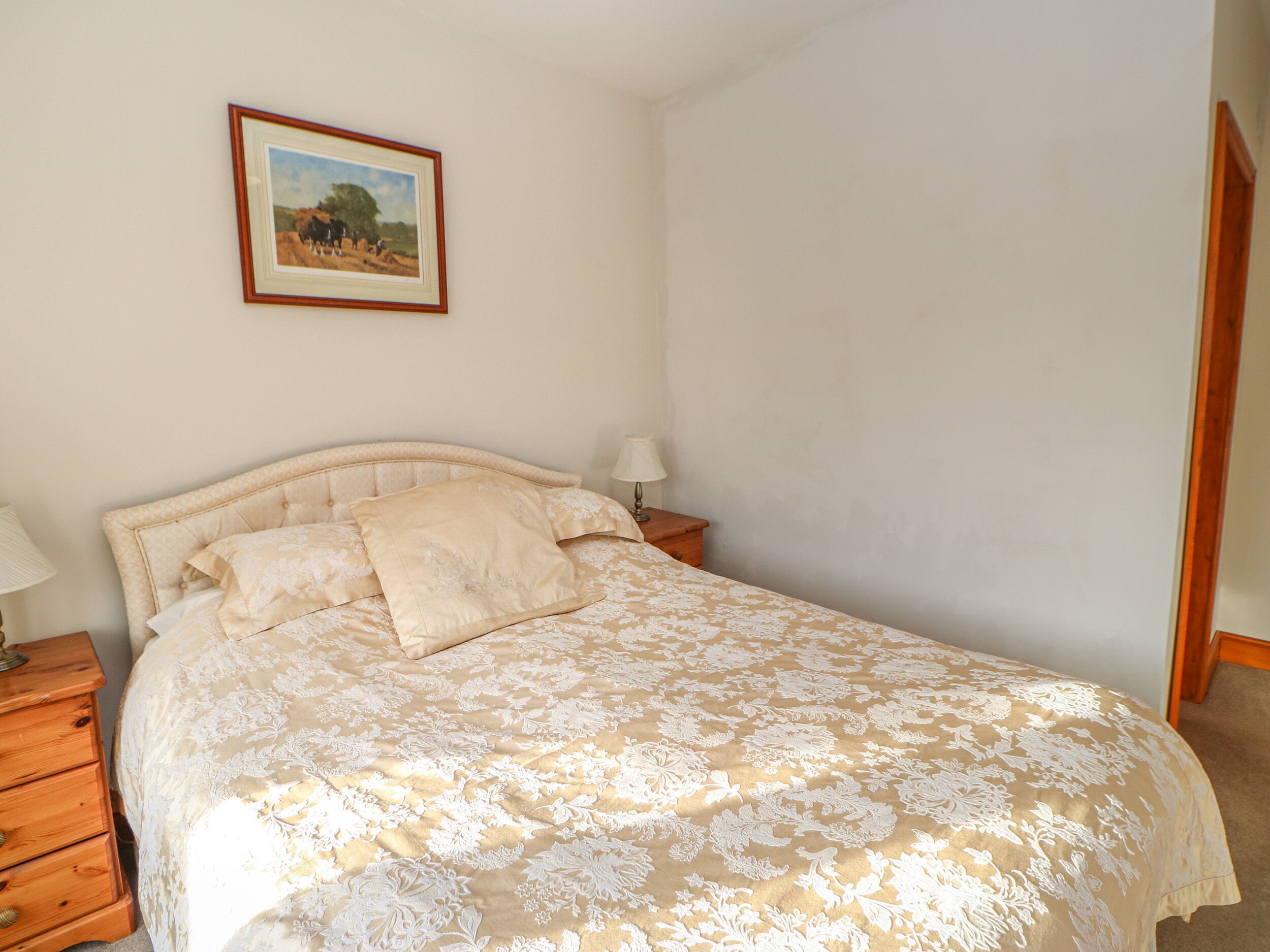A bedroom with a bed, a nightstand, a lamp, and a framed picture on the wall.