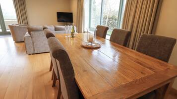 Un comedor amplio con una mesa de madera, seis sillas y un televisor montado en la pared.