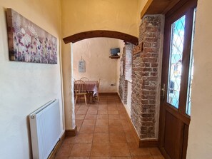 Stroll down the hallway to a charming dining area with a rustic brick wall and a view through the door.