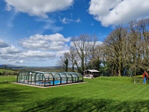 Enjoy a serene outdoor space with a greenhouse, lawn, and playground nearby.
