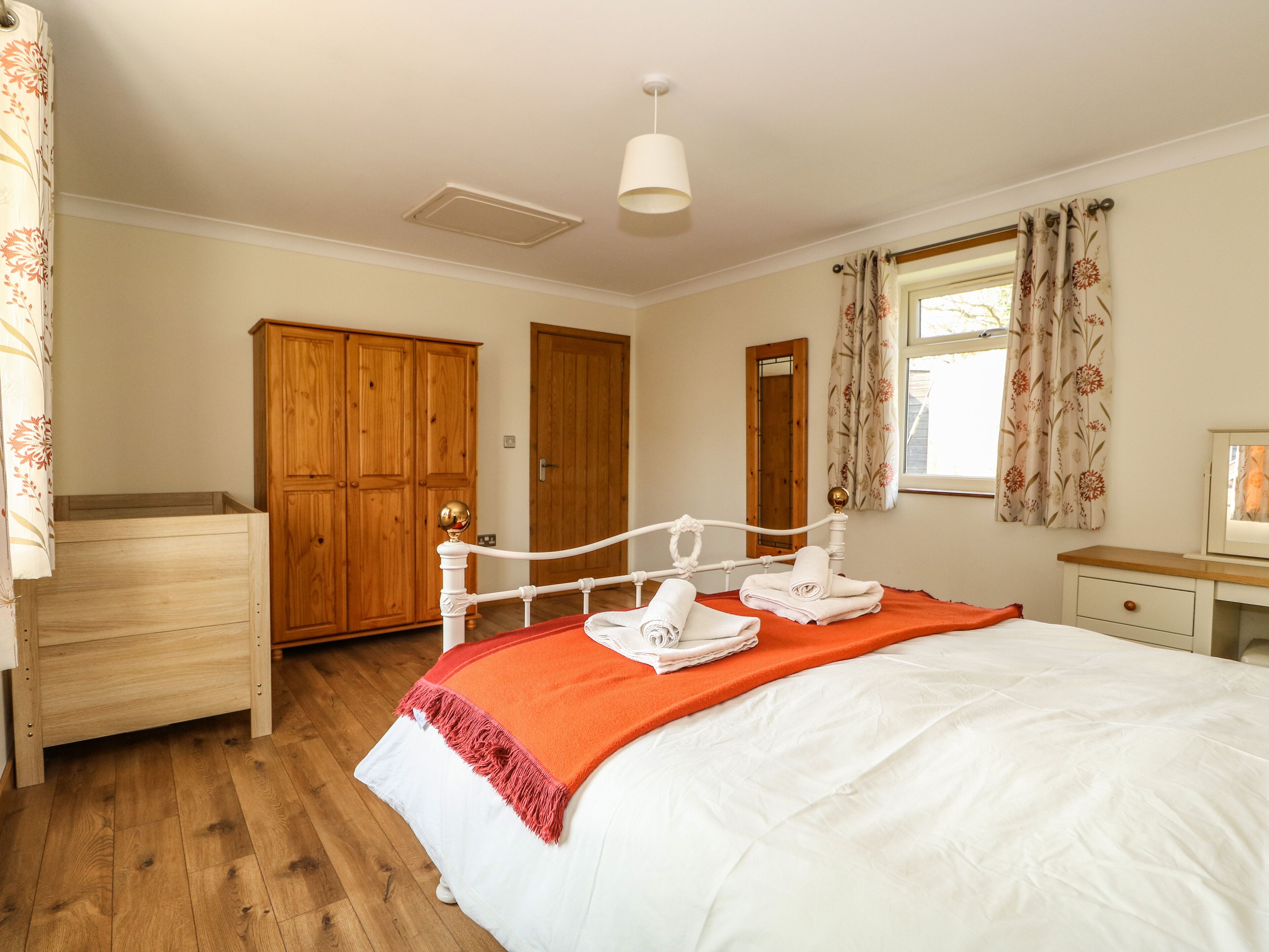 Een slaapkamer met een bed, een houten kledingkast en een raam met gordijnen.
