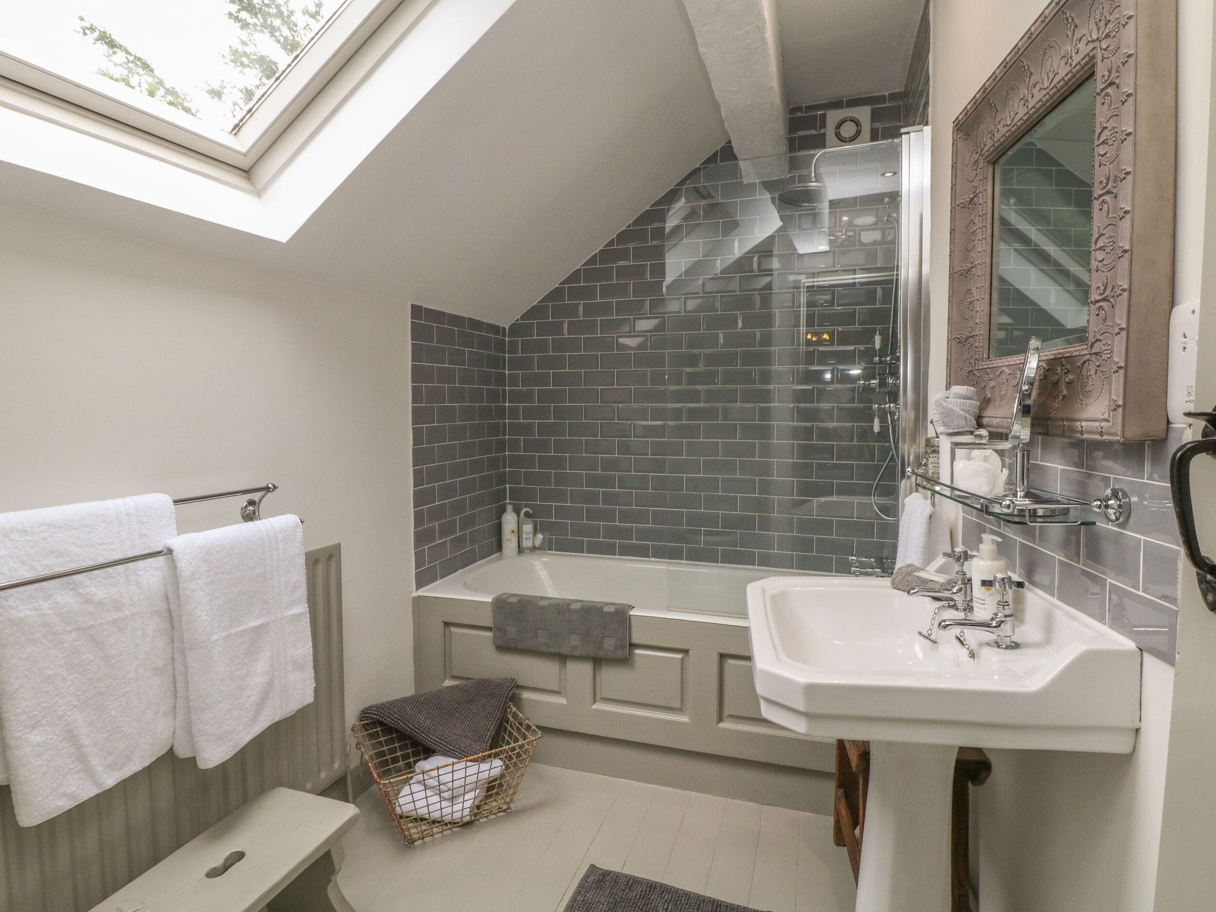 Un baño moderno con tragaluz, una bañera independiente, un tocador con espejo y una zona de ducha.