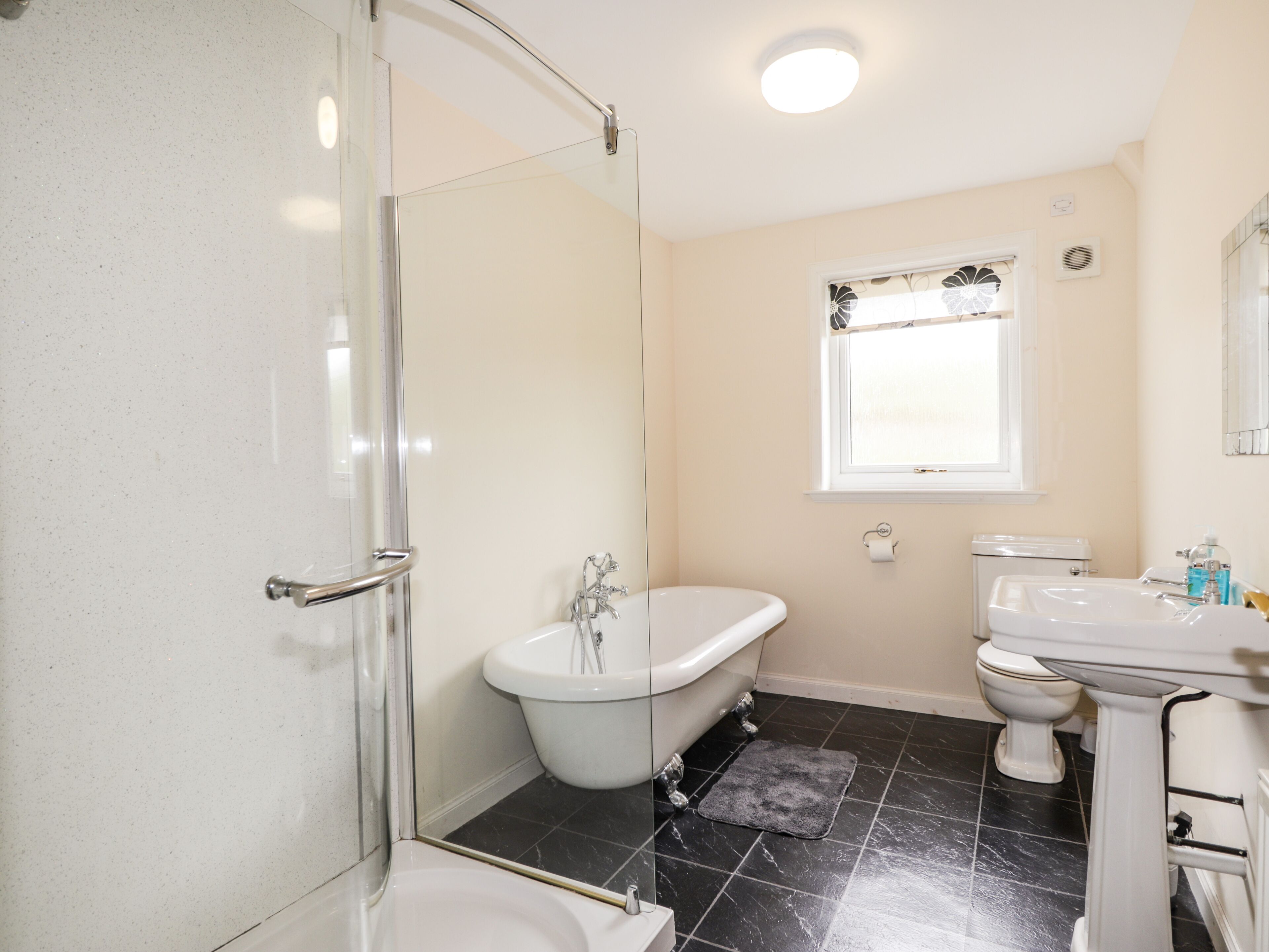 A bathroom with a glass-enclosed shower, a freestanding bathtub, a toilet, and a sink.