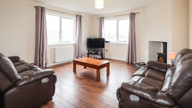 A living room with two leather sofas, a wooden coffee table, a television on a stand, and a fireplace. - Hilltop (Clachtoll)