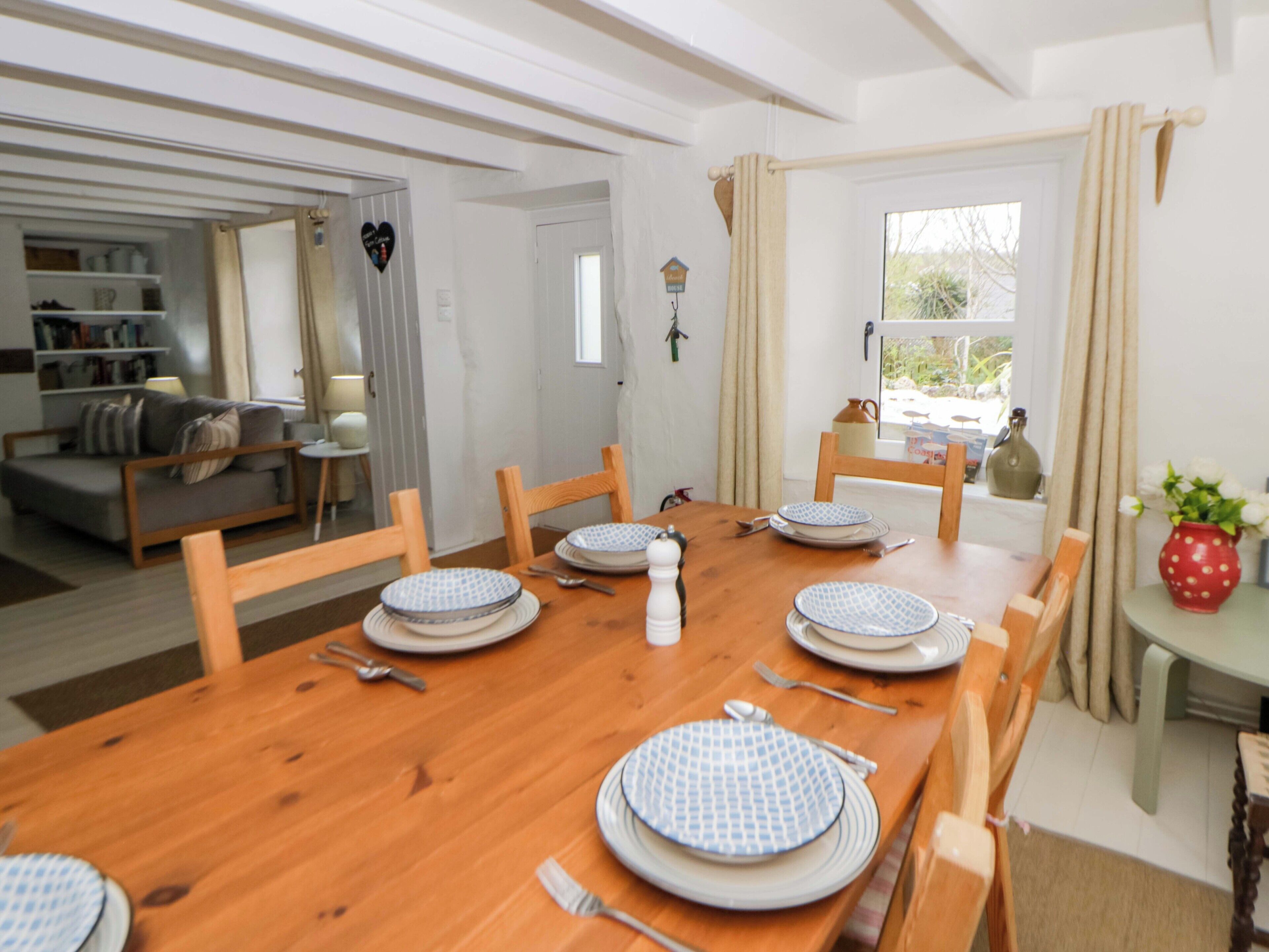 A dining area with a wooden table set for four, surrounded by chairs.