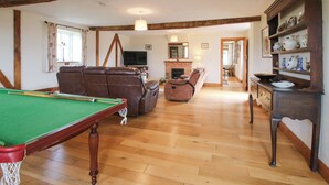 A spacious living area with a pool table, leather sofa, and a fireplace. - The Barn (Ellesmere)