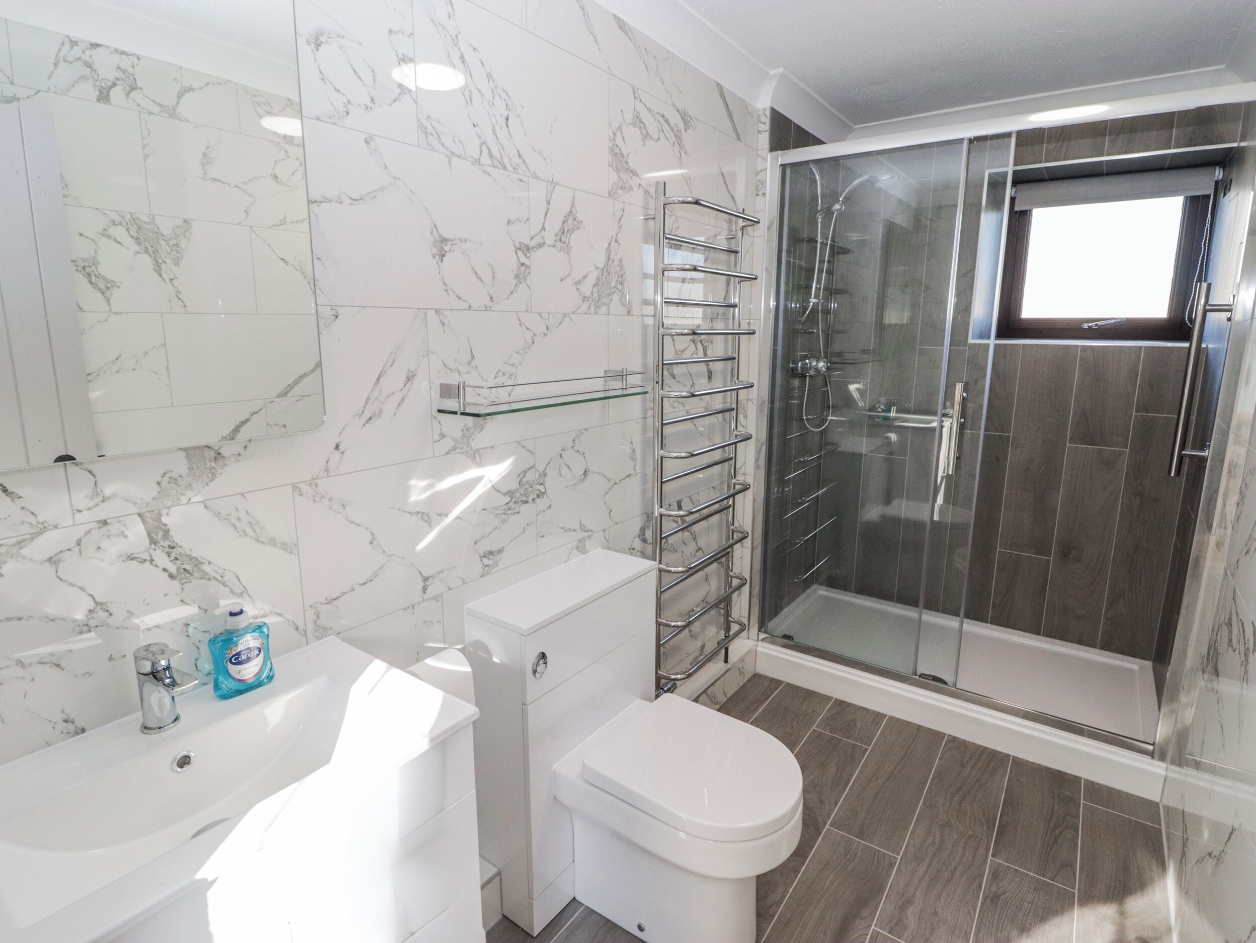 A bathroom with a toilet, sink, and glass shower enclosure.
