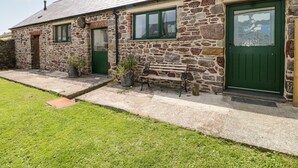 A stone cottage with a green door, a bench outside, and a small garden area. - The Long Barn (Haverfordwest)