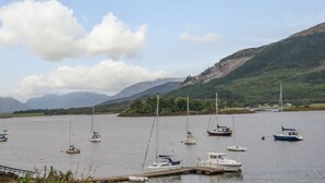 Uma marina com vários barcos atracados, rodeada por colinas e um céu limpo.