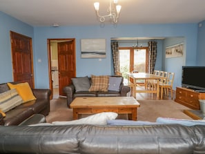 Relax in this stylish living room with a leather sofa, flat-screen TV, and dining area.