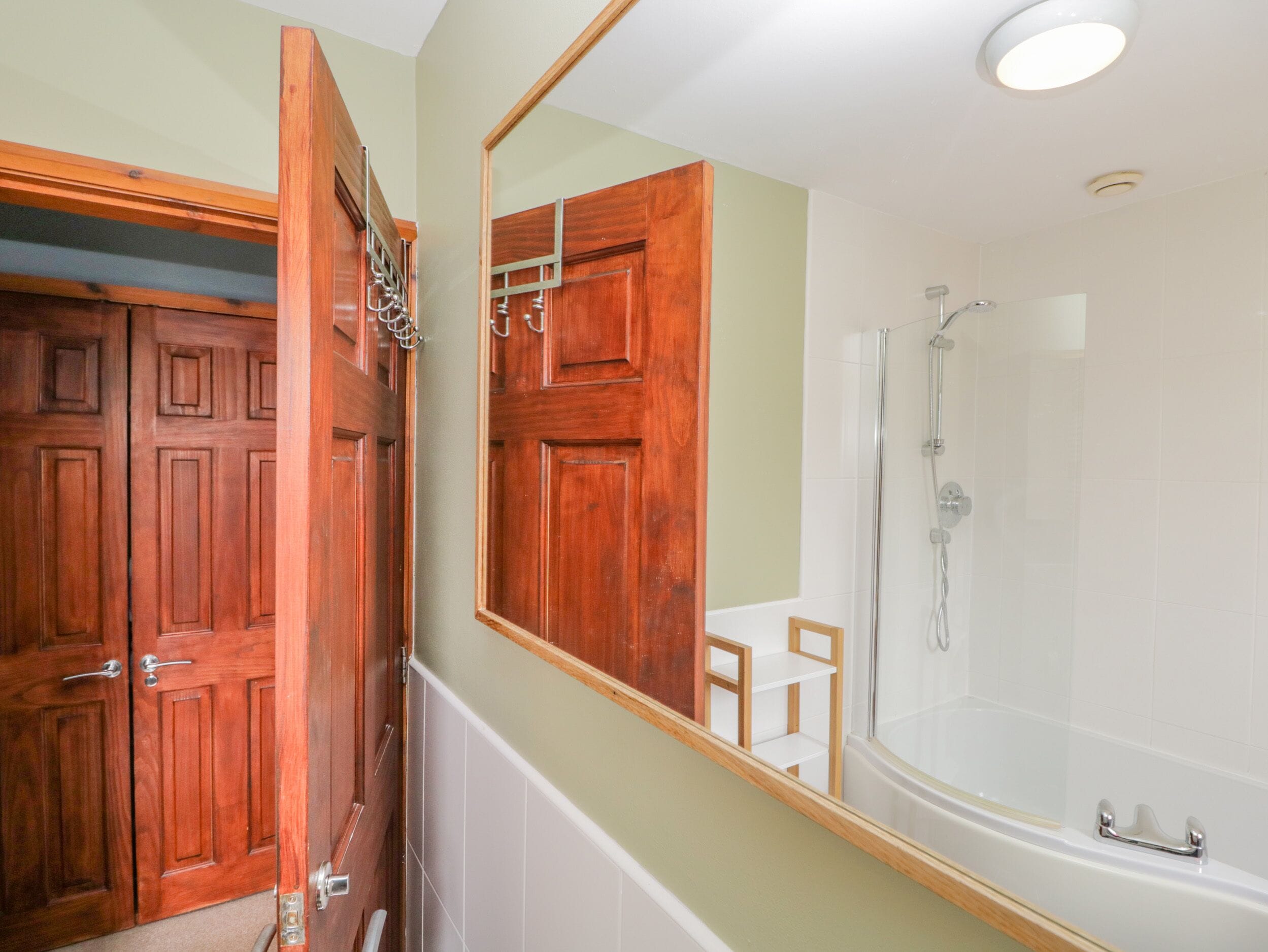 A bathroom with wooden doors, a large mirror, a shower, and a bathtub.