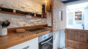 A kitchen with a stone wall, wooden cabinets, a stainless steel oven, and a wooden countertop. - Woodbine Cottage (Market Rasen)