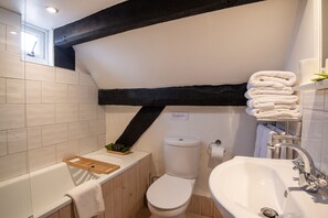 A small bathroom with a bathtub, toilet, and sink. - Woodbine Cottage (Market Rasen)