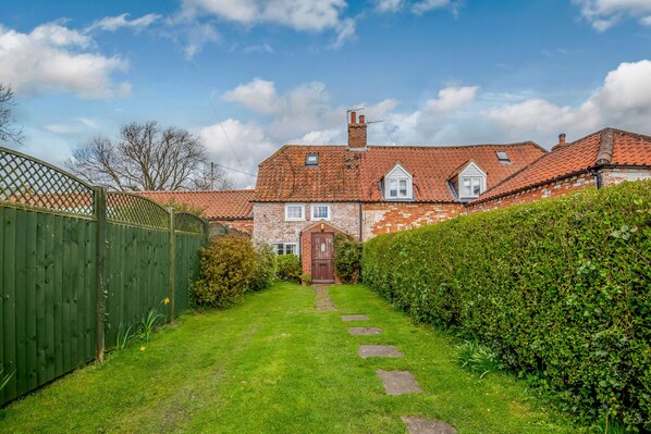 A brick house with a red-tiled roof, a wooden gate, and a well-maintained lawn. - Woodbine Cottage (Market Rasen)