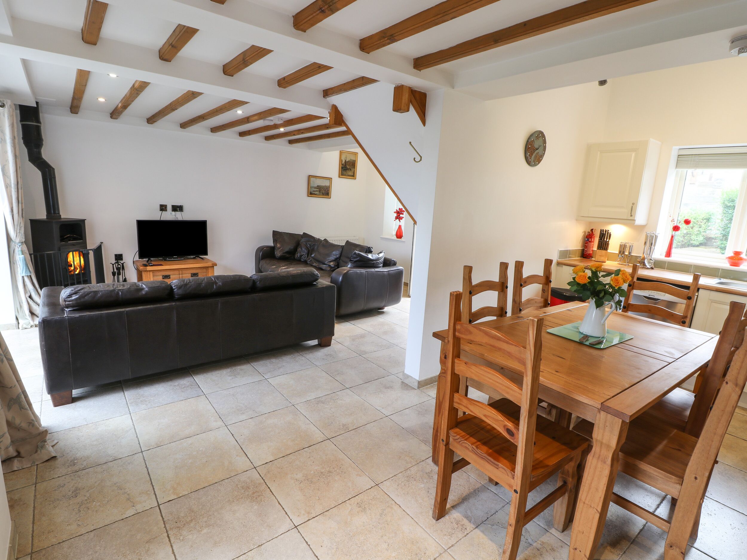 A living room with a sofa, TV, and fireplace. There's a dining area with a table and chairs.