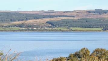 A lake with a town in the distance, surrounded by hills and trees.