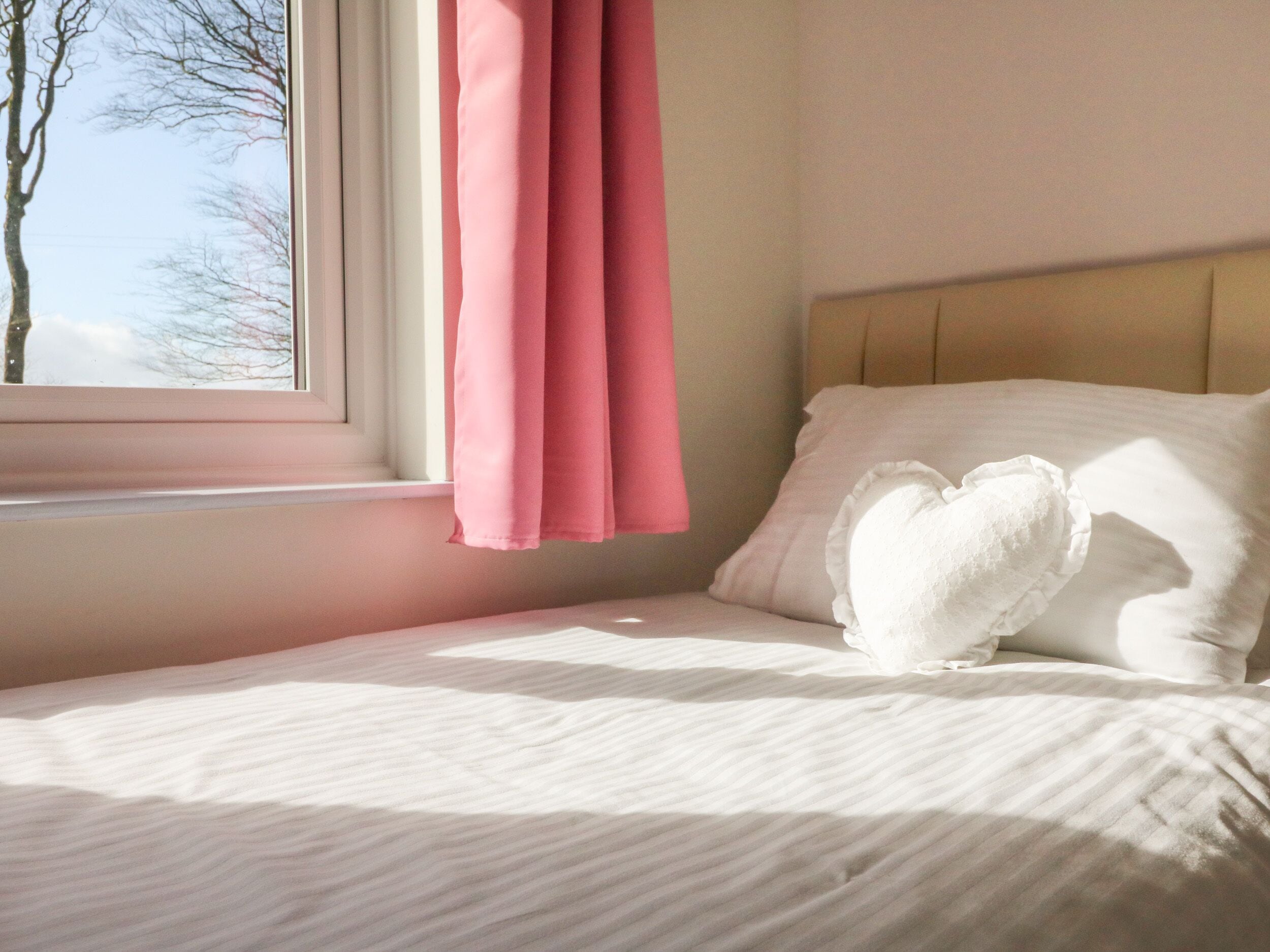 A bedroom with a bed, a window with curtains, and a view of trees outside.