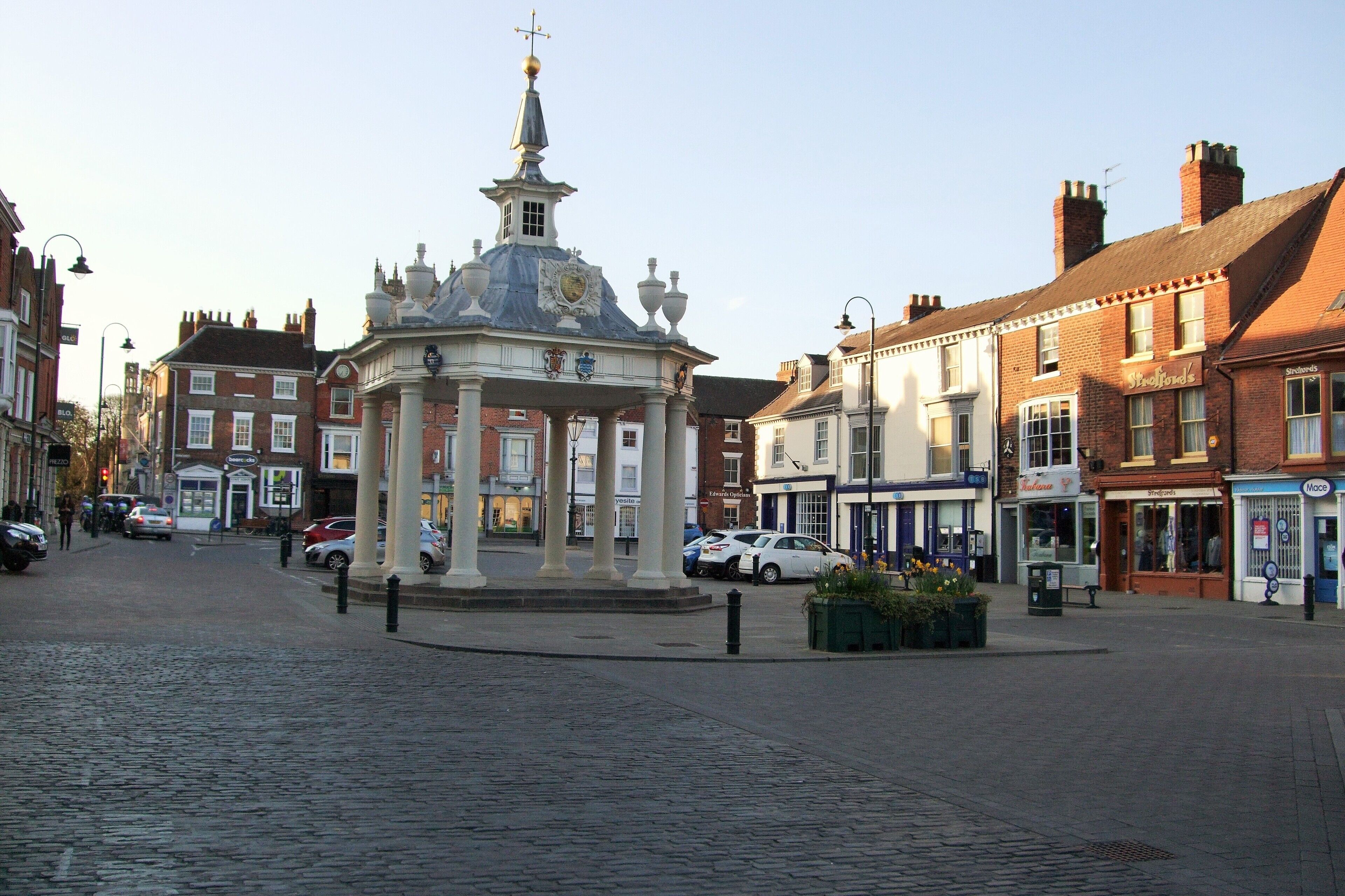 A cobblestone street with a central pavilion featuring a dome and columns, surrounded by traditional buildings with shops.