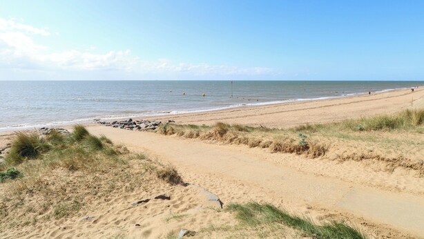 A sandy beach with a clear sky and calm sea. - Fern Cottage (King's Lynn)