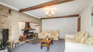 A cozy living room with a fireplace, a sofa, a coffee table, and a television.